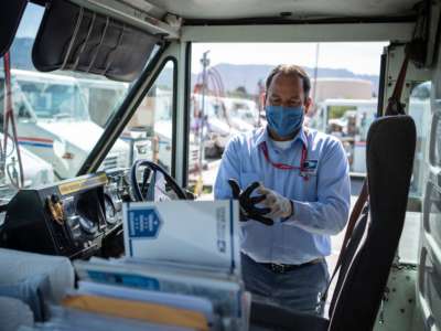 A mail carrier dons blue gloves