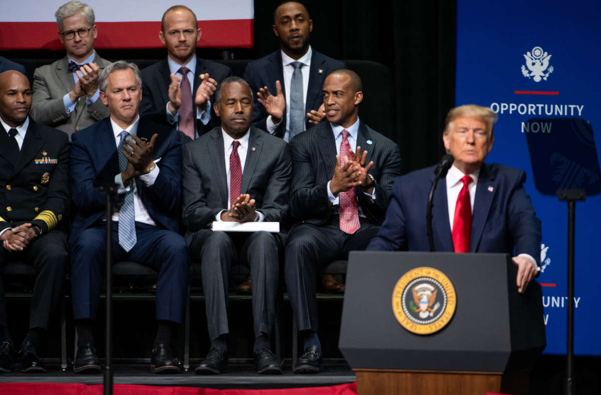Housing and Urban Development Secretary Ben Carson, center, applauds with other guests as President Trump addresses the crowd during the Opportunity Now summit at Central Piedmont Community College on February 7, 2020, in Charlotte, North Carolina.