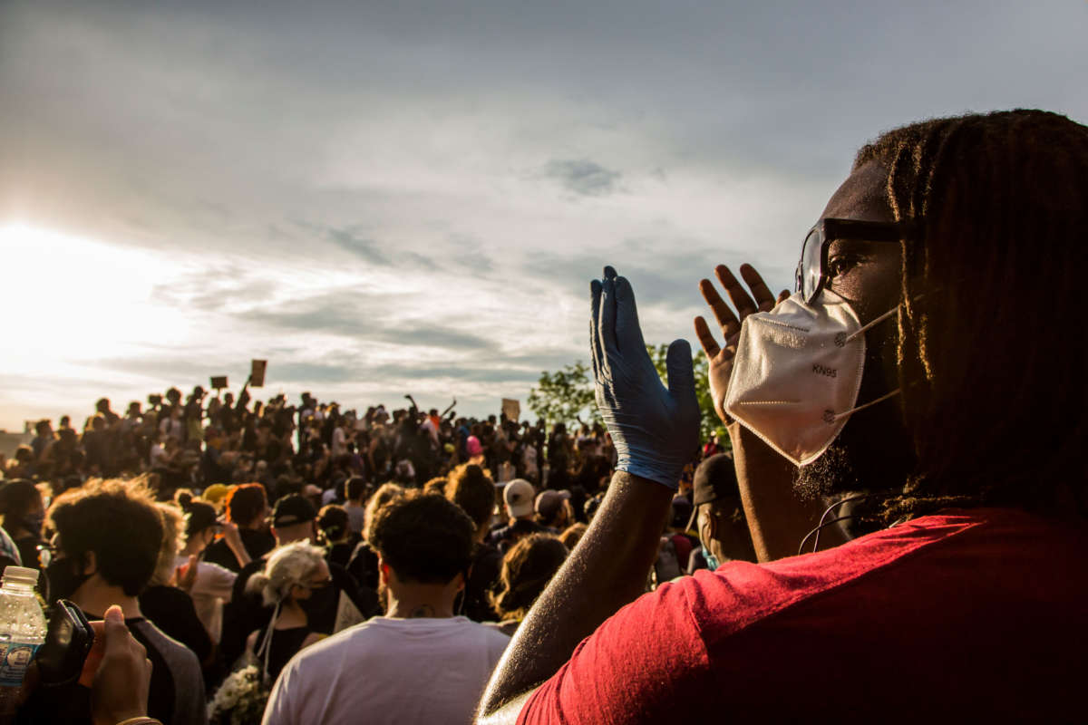 A protester wearing a protective mask applauds during a protest against the death of George Floyd on June 3, 2020, in Brooklyn, New York.