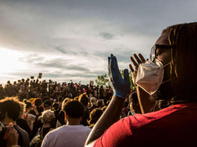 A protester wearing a protective mask applauds during a protest against the death of George Floyd on June 3, 2020, in Brooklyn, New York.