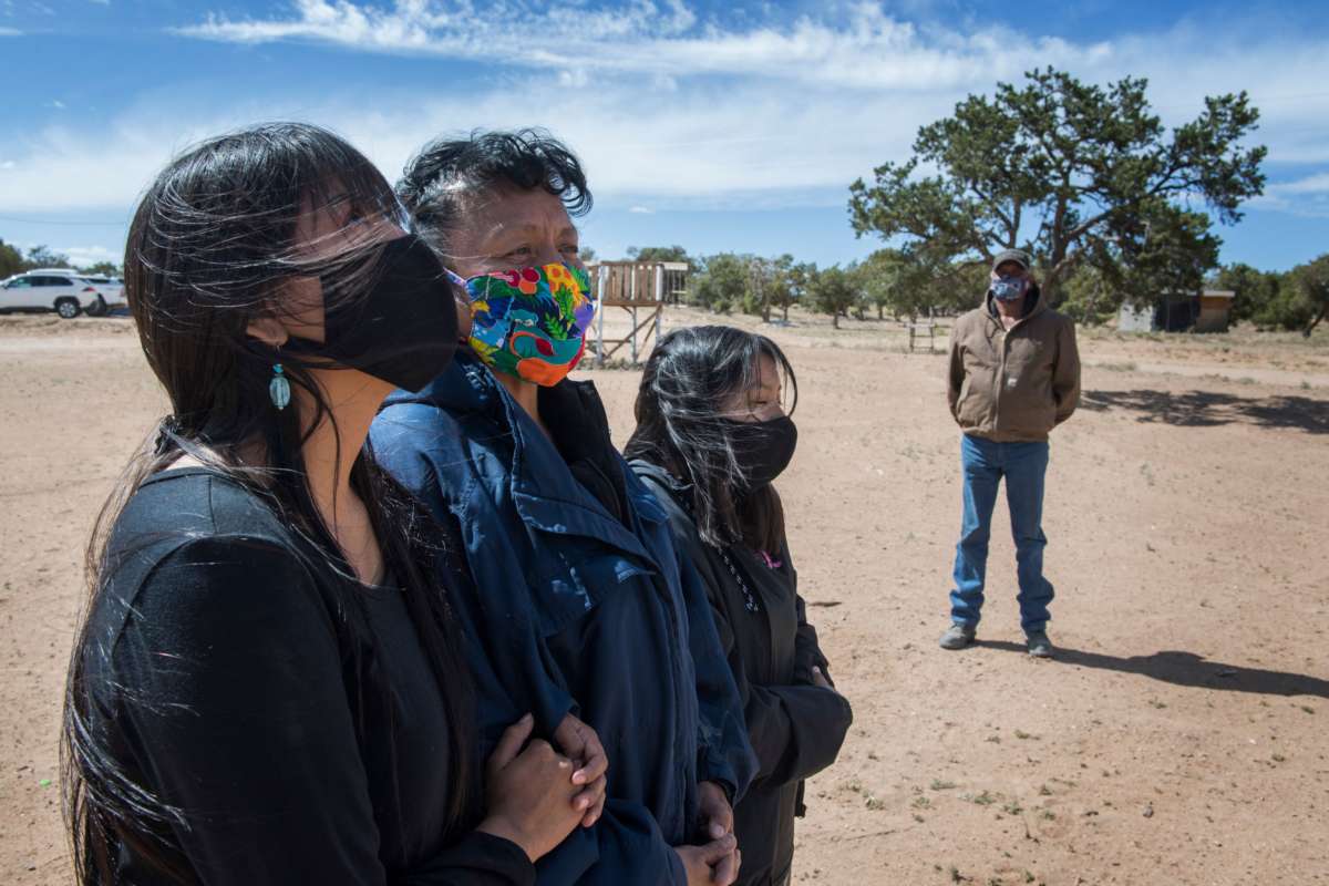 Two Navajo women and a girl stand next to eachother with facemasks on as an Elder, also in a facemask, looks on