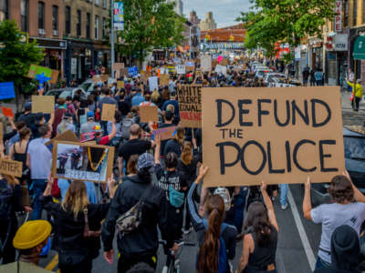 Participants hold a "Defund The Police" sign at the protest, on June 2, 2020. Thousands of protesters filled the streets of Brooklyn in a massive march to demand justice for George Floyd.