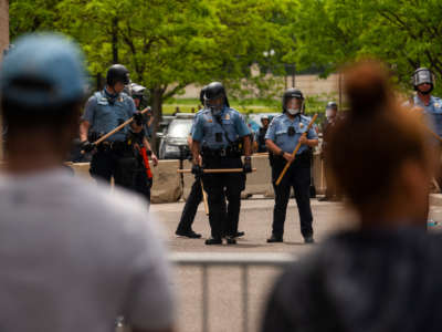 Police officers stand in a line while facing protesters outside the Third Police Precinct on May 27, 2020, in Minneapolis, Minnesota.