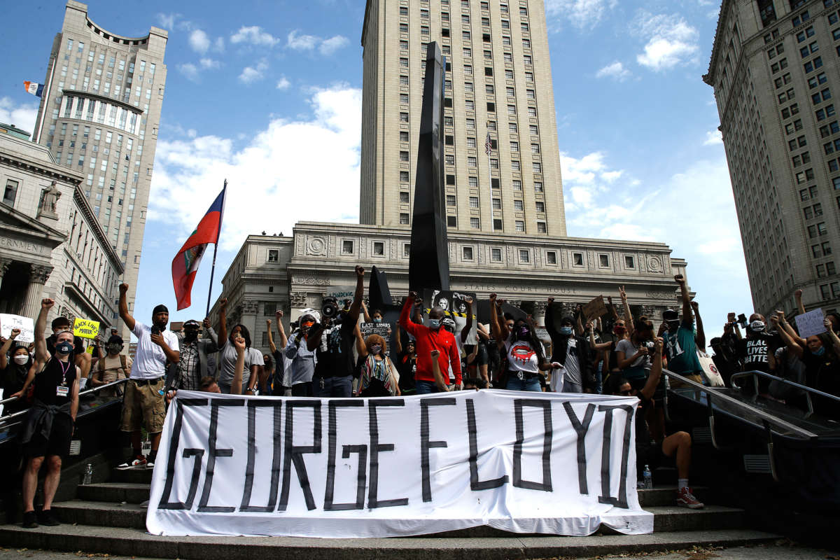 Protesters raise fists en masse while displaying a banner reading "GEORGE FLOYD"