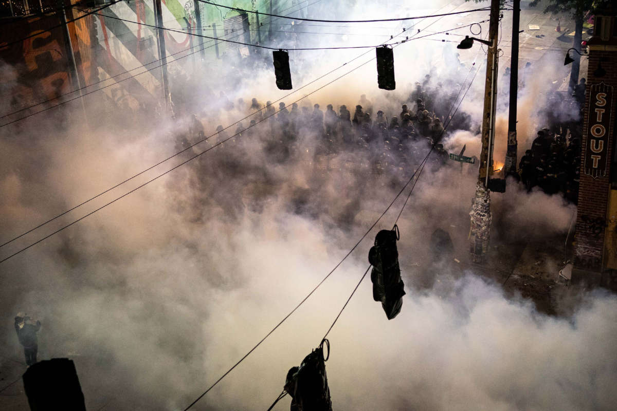 Police are seen through tear gas filling the air near the Seattle Police Department's East Precinct, shortly after midnight on June 8, 2020, in Seattle, Washington.