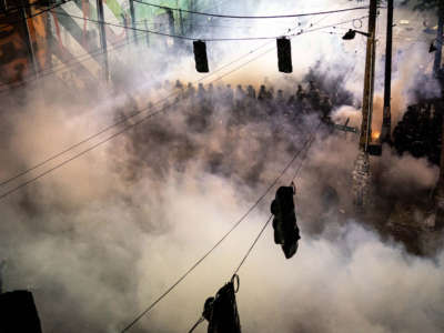 Police are seen through tear gas filling the air near the Seattle Police Department's East Precinct, shortly after midnight on June 8, 2020, in Seattle, Washington.