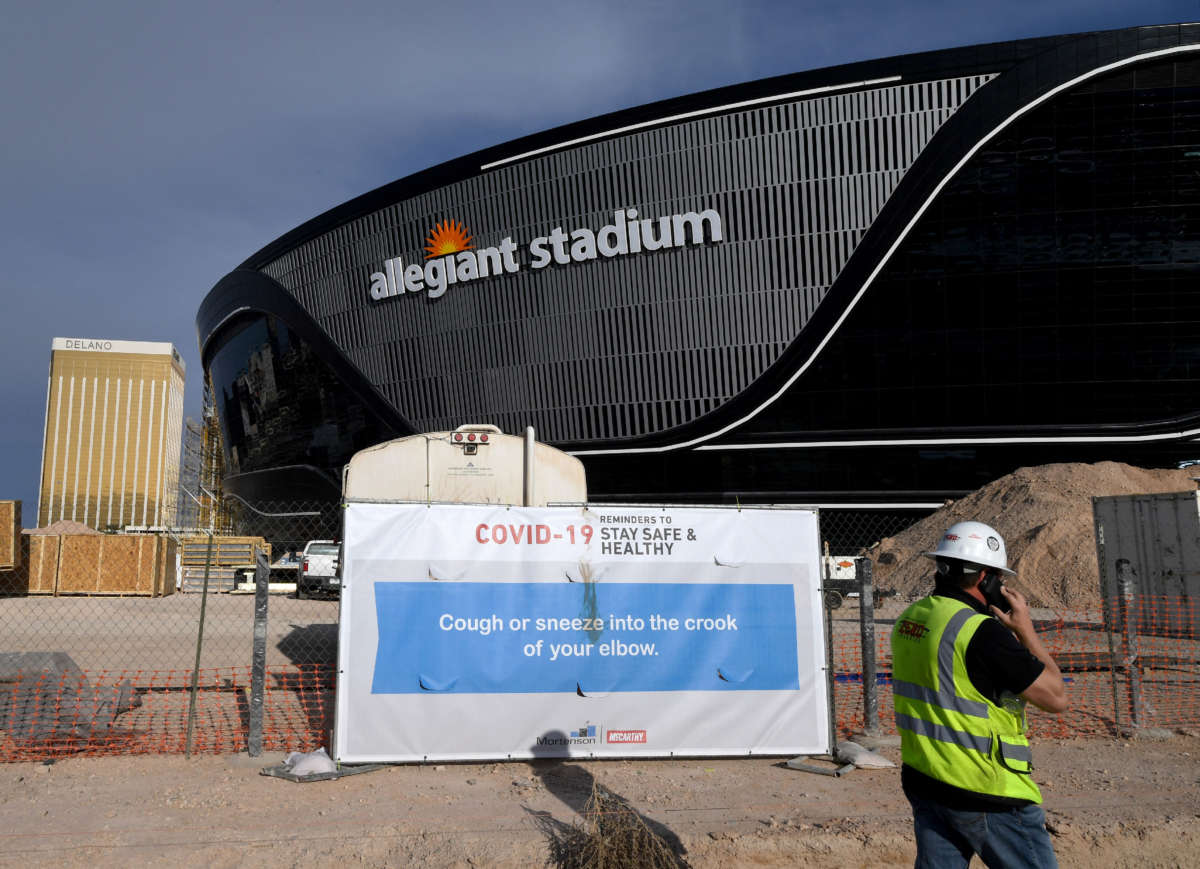 A sign with guidelines for how to stay safe from the coronavirus is posted on a fence at Allegiant Stadium as construction continues on the 2 billion dollar, glass-domed future home of the Las Vegas Raiders