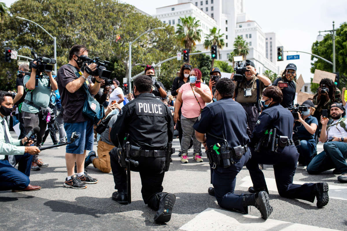 LAPD officers take a knee with clergy and marchers at LAPD Headquarters during a demonstration demanding justice for George Floyd on June 2, 2020, in Los Angeles, California.