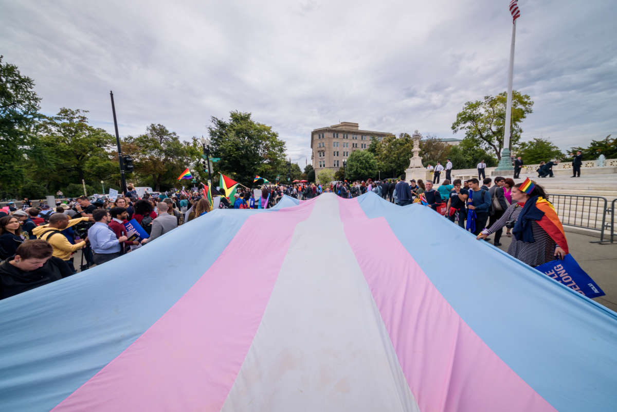 Activists stretch the trans flag out on the steps of the supreme court building