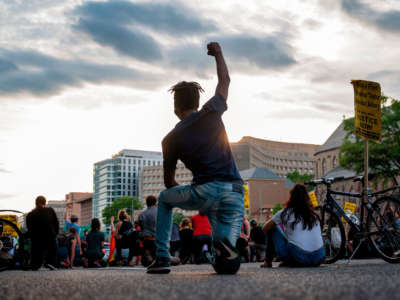 A protester kneels and holds up a fist as he and others demonstrate against the death of George Floyd by closing down and blocking traffic on I-395 in Washington, D.C., on June 15, 2020.