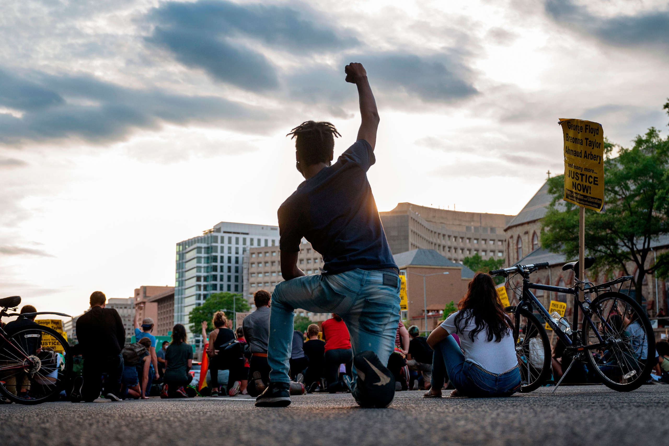 A protester kneels and holds up a fist as he and others demonstrate against the death of George Floyd by closing down and blocking traffic on I-395 in Washington, D.C., on June 15, 2020.