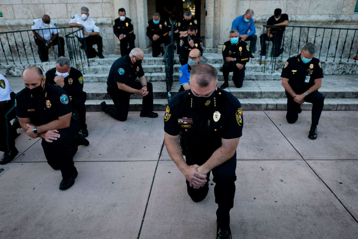 Police officers kneel during a rally in Coral Gables, Florida, on May 30, 2020, in response to the recent death of George Floyd.