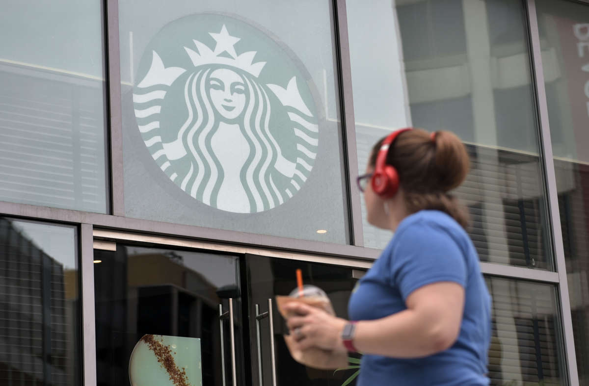 A woman looks up at a starbuck's logo