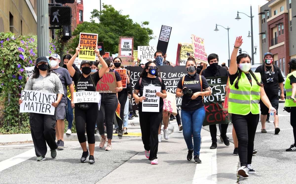 Masked protesters march while holding sineage