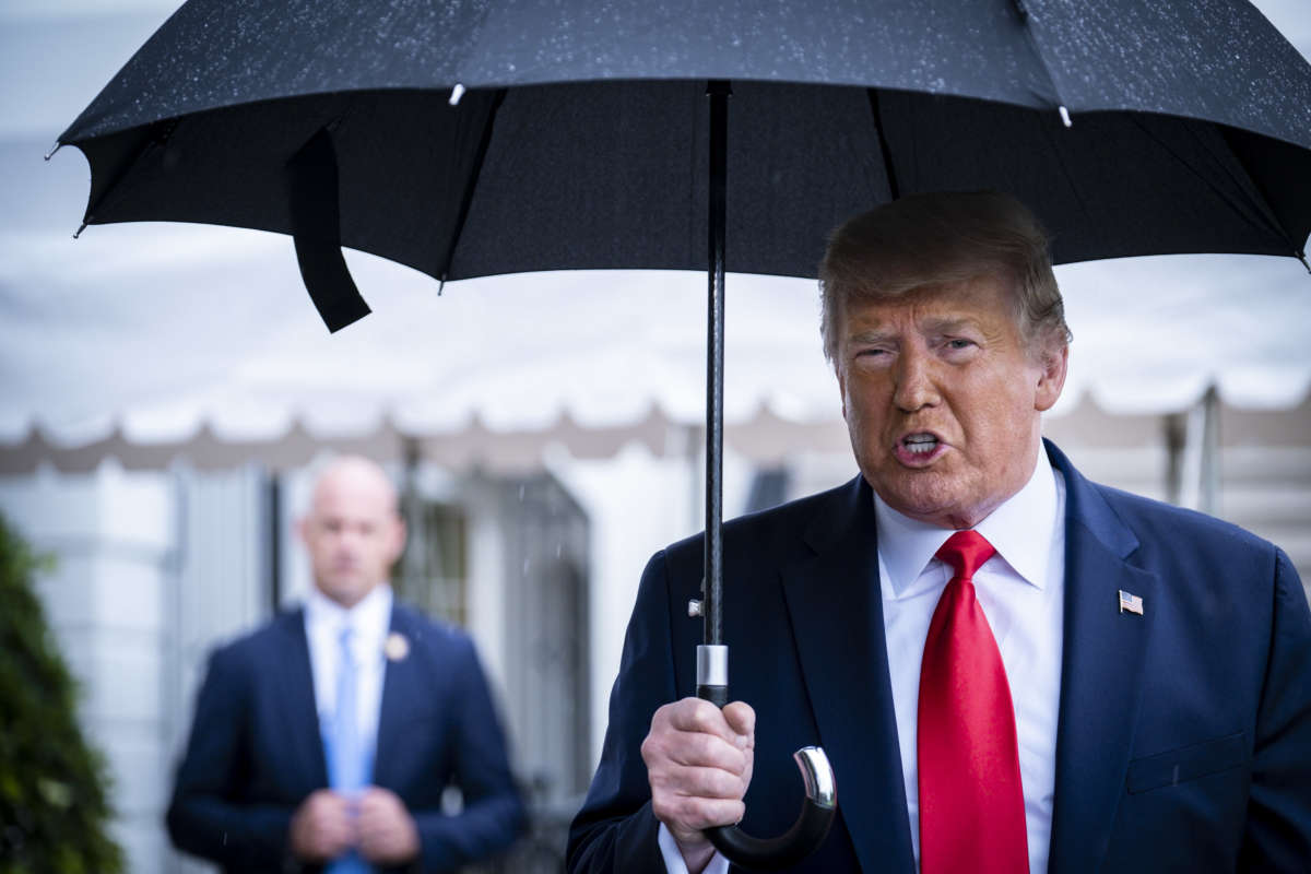 Donald Trump speaks while holding an umbrella in the rain