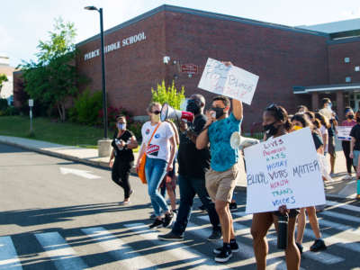 A demonstration of Milton teachers and community members passes in front of the Pierce Middle School on Juneteenth, June 19, 2020, in Milton, Massachussetts.