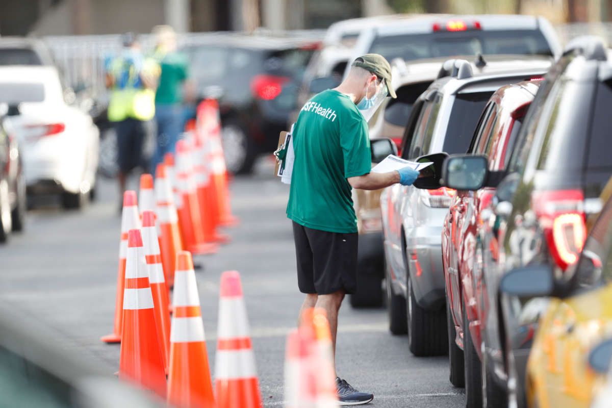 A University of South Florida Health administrator talks to a driver before they receive a coronavirus test at the Lee Davis Community Resource Center on June 25, 2020, in Tampa, Florida.