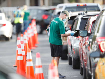 A University of South Florida Health administrator talks to a driver before they receive a coronavirus test at the Lee Davis Community Resource Center on June 25, 2020, in Tampa, Florida.