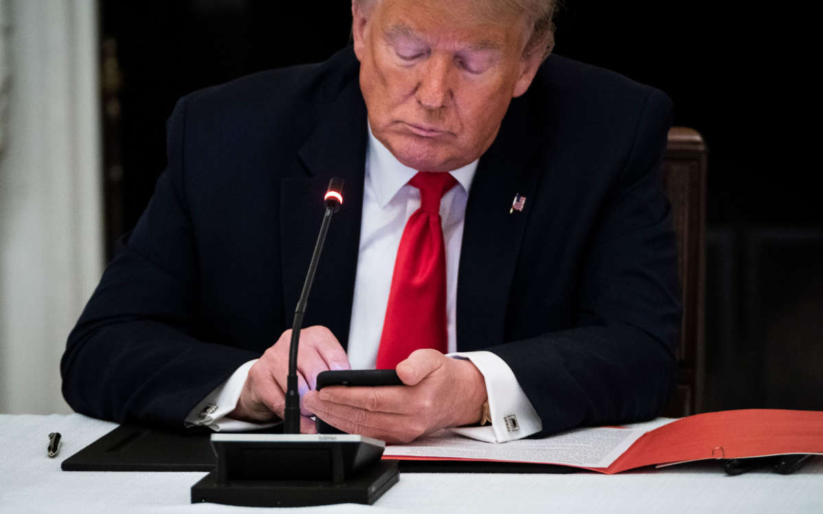 President Trump uses his cellphone as he participates in a roundtable discussion in the State Dinning Room at the White House on June 18, 2020, in Washington, D.C.