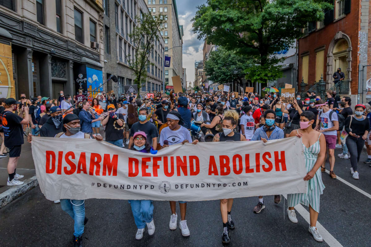 Participants hold a banner in front of the crowd marching in Manhattan, on June 29, 2020.