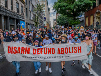 Participants hold a banner in front of the crowd marching in Manhattan, on June 29, 2020.