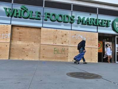 People go shopping at a Whole Foods Market store, which is boarded up after a night of protest over the police killing of George Floyd in Minneapolis on June 1, 2020, in the Brooklyn borough of New York City.
