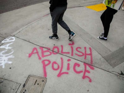 The words "Abolish Police" are spray painted on the sidewalk as people gathered to protest the death of George Floyd and in support of Black Lives Matter, in Los Angeles, CA, on June 5, 2020.