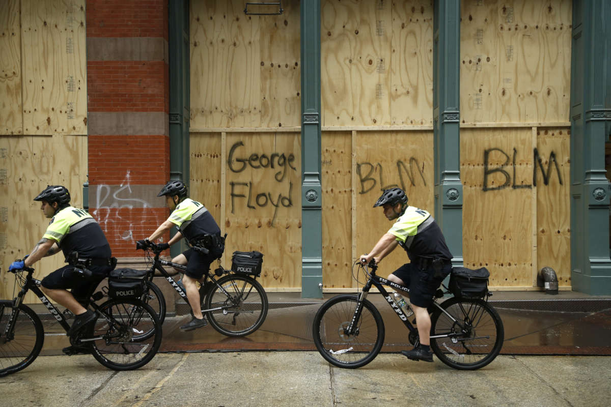 Police ride bikes past a boarded up store during a march against police brutality and racial justice on June 11, 2020, in New York City.