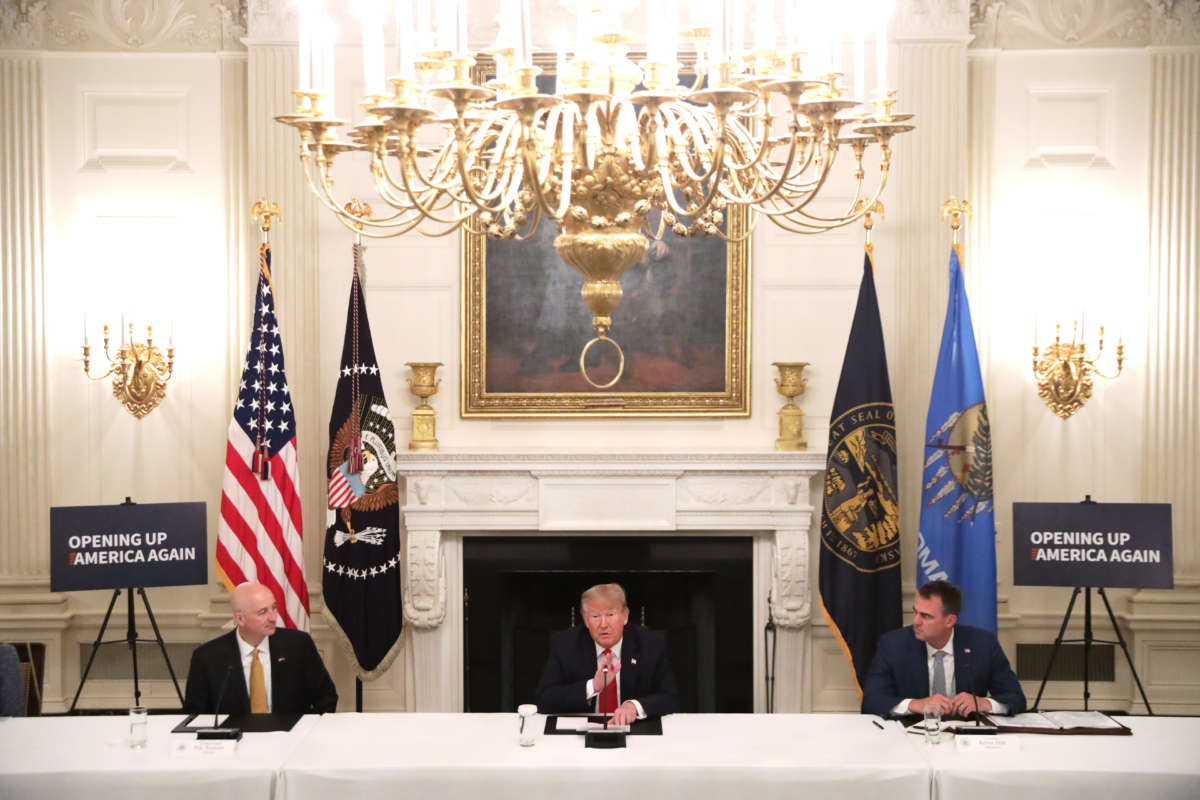 President Donald Trump speaks as Gov. Pete Ricketts (left) and Governor Kevin Stitt listen during a roundtable at the State Dining Room of the White House on June 18, 2020, in Washington, D.C.