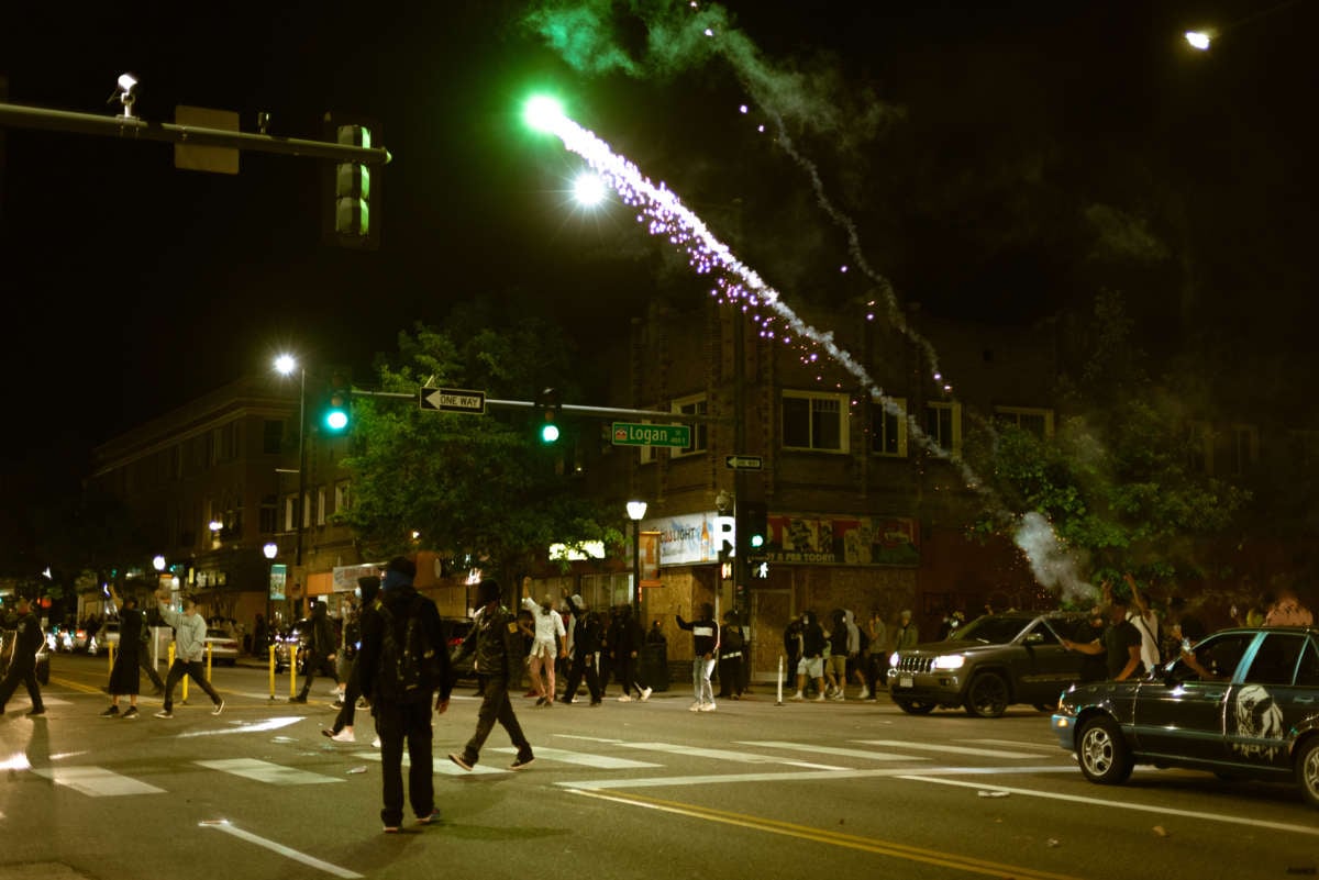 people walk in the street as fireworks are lit
