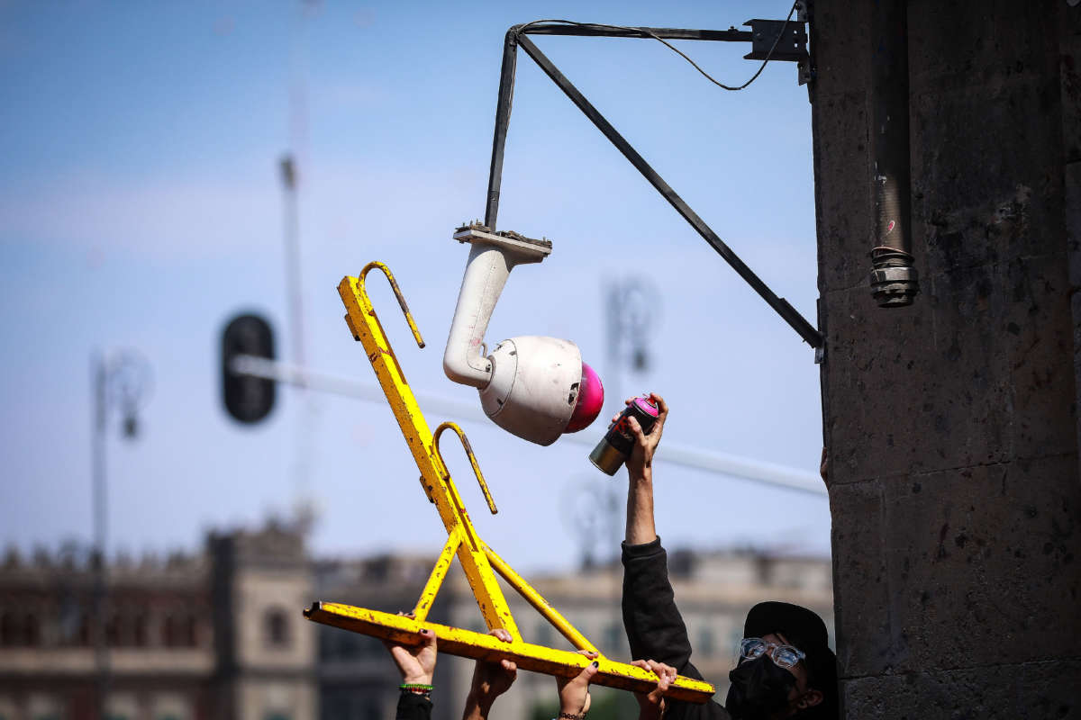 A man paints a security camera during a protest against police brutality in Mexico City, Mexico, on June 8, 2020.