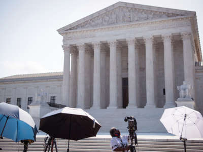 A journalist sets up lighting equipment on the steps of the supreme court building