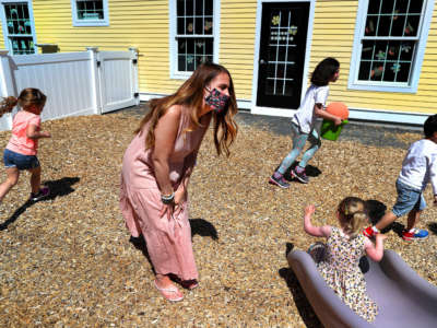 Preschool teacher Jenna Grenier keeps an eye on the children playing in the outside play area at Magical Beginnings Learning Academy in Middleton, Massachusetts, on May 22, 2020.