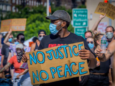 A participant holds a No Justice No Peace sign at a protest in Brooklyn, New York, July 4, 2020.