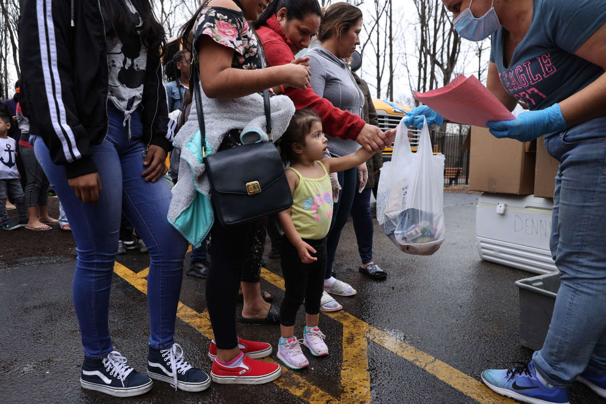 Dozens of families receive food distributed by Montgomery County Public Schools as part of a program to feed children while schools are closed due to the coronavirus, March 20, 2020, in Silver Spring, Maryland.