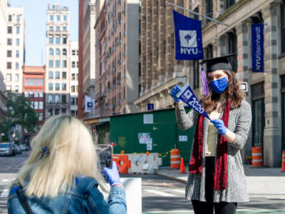 A student celebrates her graduation in a surgical mask