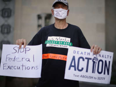 An elderly man holds signs opposing the death penalty