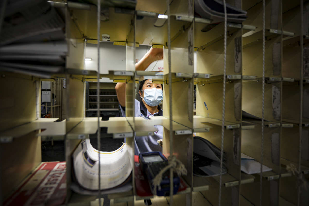 A postal worker puts mail into cubbies