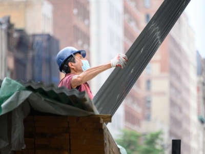 A worker handles siding during a construction job