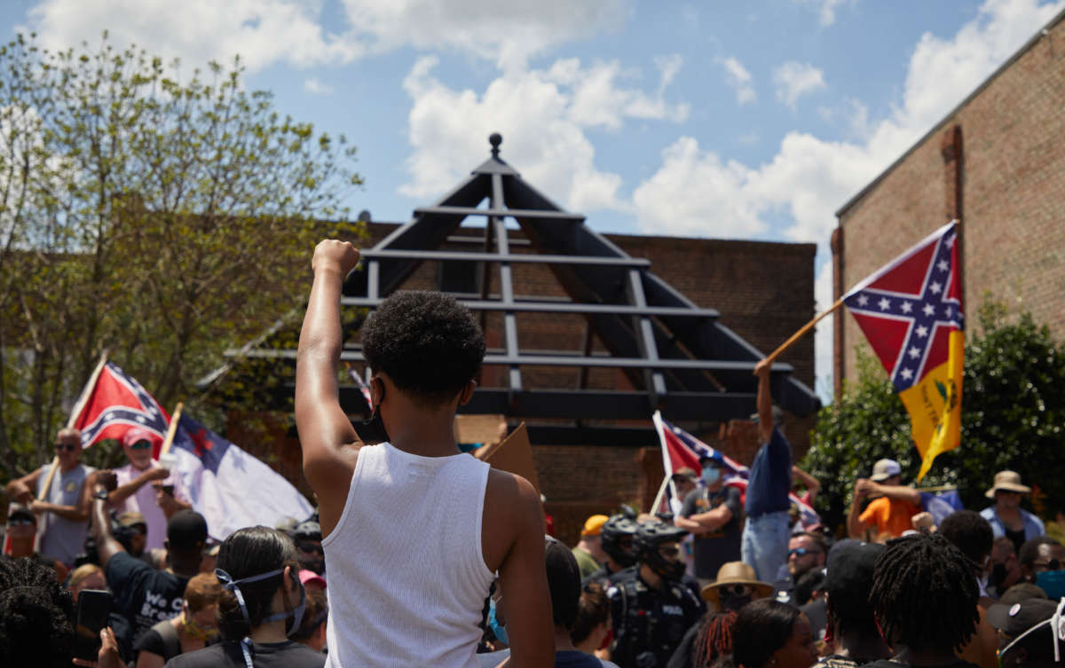Anti-racist protesters raise fists toward supporters of the Confederacy at the Alamance County Courthouse at a rally with the Burlington-Alamance March For Justice and Community in Graham, North Carolina, on July 11, 2020.