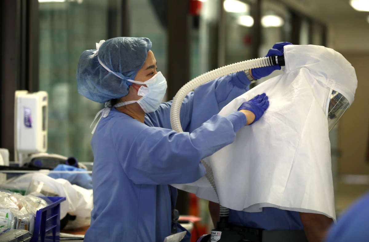 A nurse helps a doctor remove his personal protective equipment after leading a team that performed a procedure on a COVID-19 patient in the intensive care unit at Regional Medical Center on May 21, 2020, in San Jose, California.