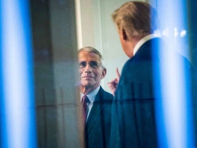 President Trump, seen through a window, speaks with Dr. Anthony Fauci, director of the National Institute of Allergy and Infectious Diseases, in the press office at the White House on April 22, 2020, in Washington, D.C.