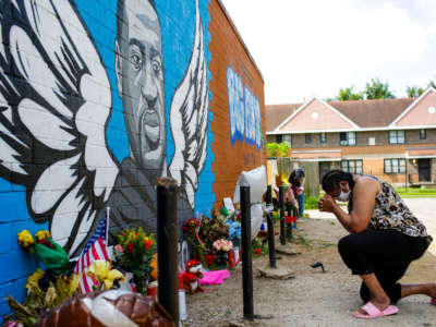 A woman prays outside Scott Food Mart at a makeshift memorial and a mural for George Floyd in the 3rd Ward on June 9, 2020, in Houston, Texas.