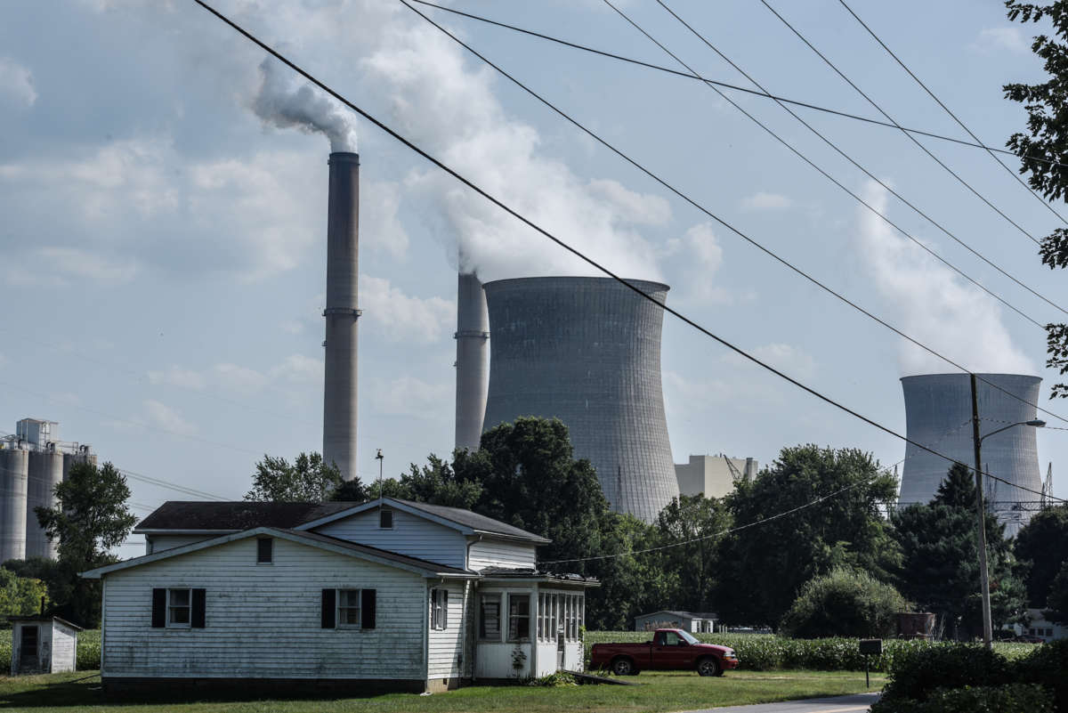 A power plant billows smoke into the air behind a house