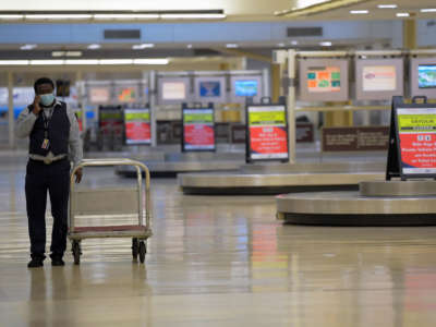 An American Airlines worker walks among a deserted baggage claim area at Reagan National Airport in Arlington, Virginia, on April 30, 2020.