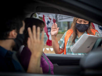 U.S. Citizenship and Immigration Services officer Rochelle Reyes, right, administers the oath of allegiance to a mother and son during a drive-through citizenship naturalization at the Chet Holifield Federal Building parking lot, June 23, 2020, in Laguna Niguel.