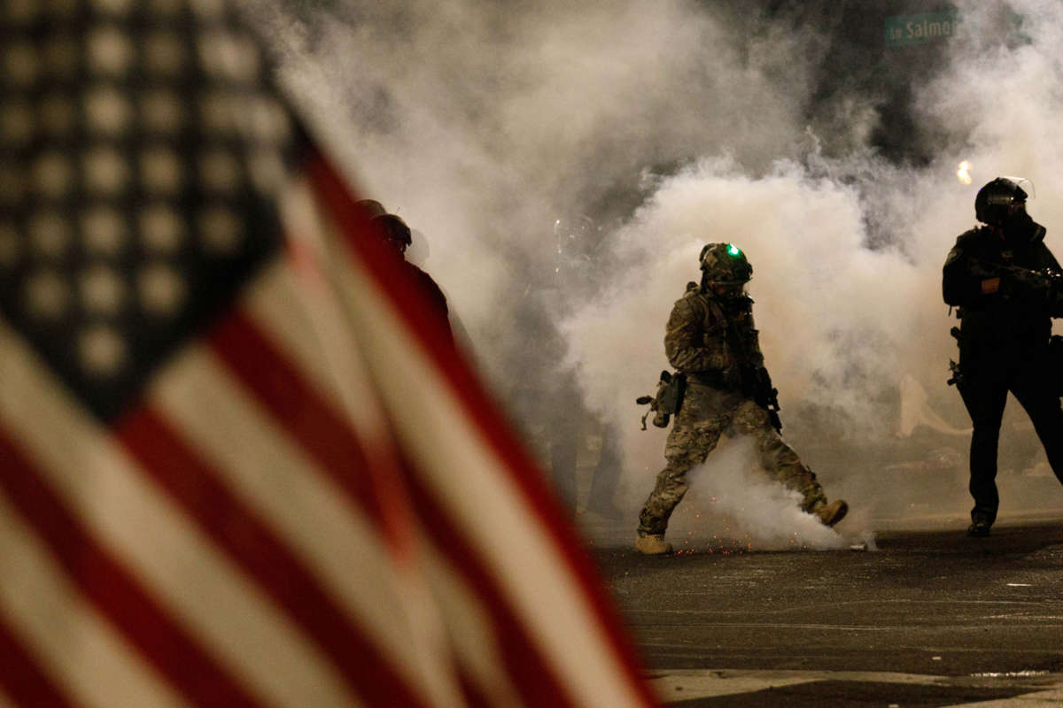 Federal officers shoot tear gas at moms while one of their bretheren flaps a u.s. flag in the foreground