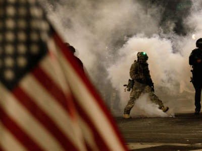 Federal officers shoot tear gas at moms while one of their bretheren flaps a u.s. flag in the foreground