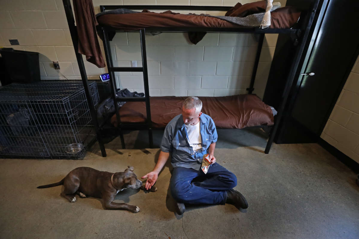 A man feeds a dog a treat in a jail cell