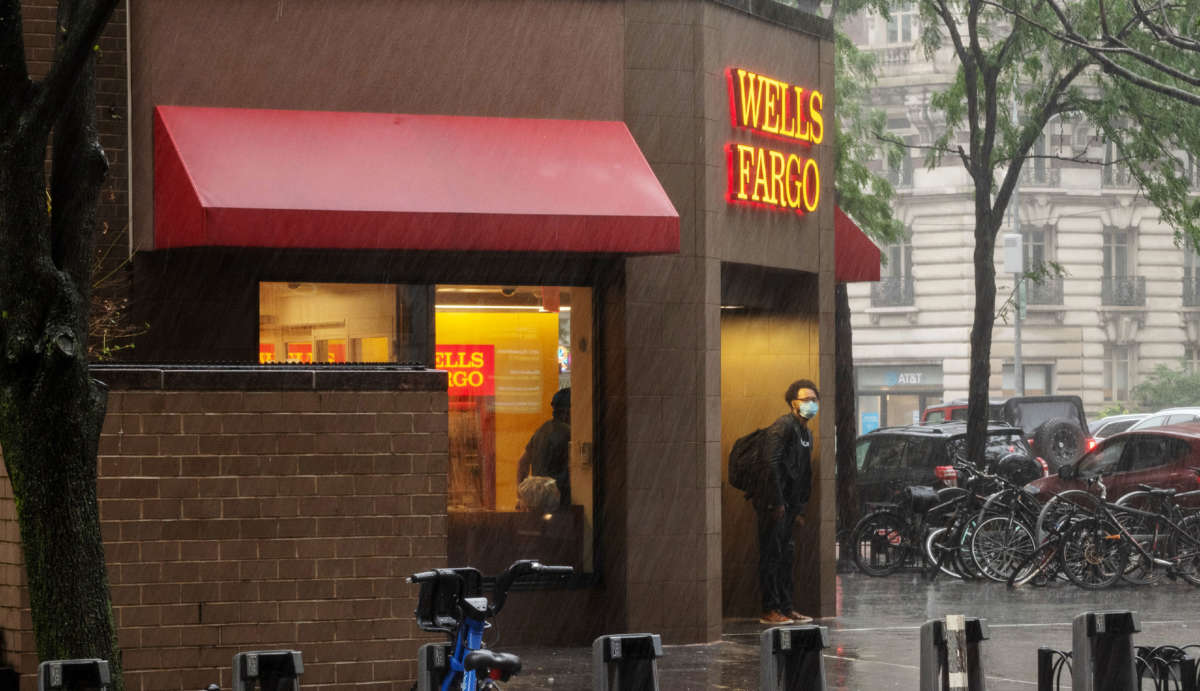 A person wearing a mask stands under a Wells Fargo awning in the rain on July 9, 2020, in New York City.